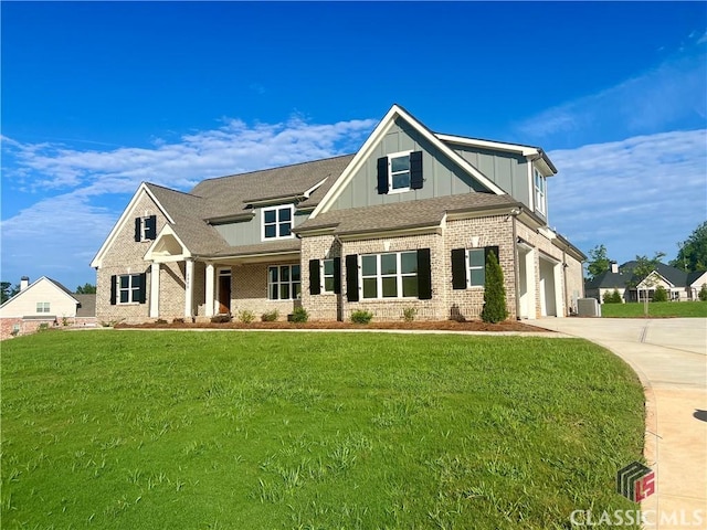 view of front facade featuring driveway, a front yard, board and batten siding, and brick siding