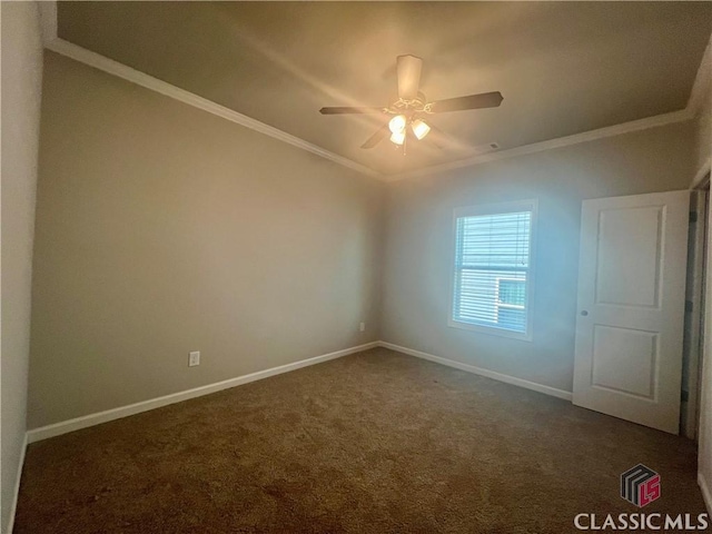 unfurnished room with baseboards, dark carpet, ceiling fan, and crown molding