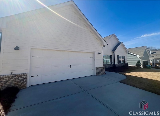 view of property exterior with driveway, a garage, and brick siding