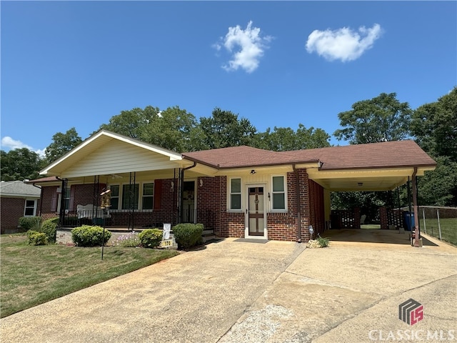 view of front facade featuring driveway, brick siding, a porch, a carport, and a front yard