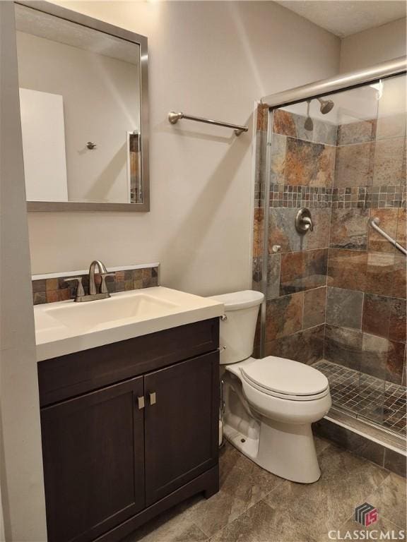 bathroom with toilet, a shower stall, and vanity