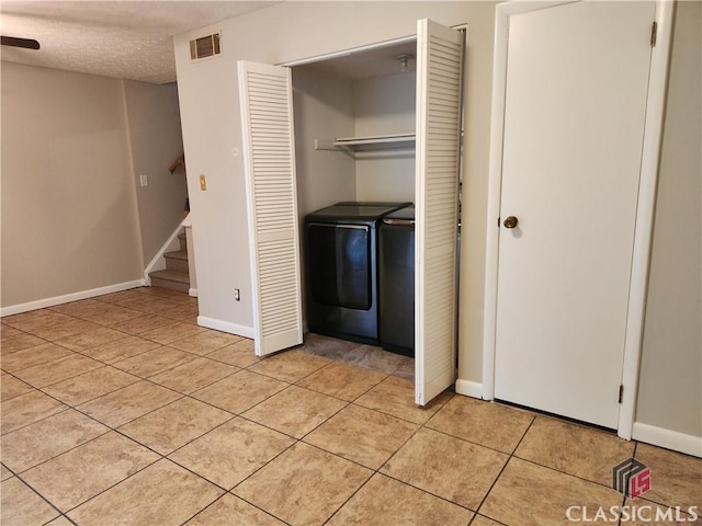 clothes washing area featuring baseboards, visible vents, laundry area, light tile patterned flooring, and a textured ceiling