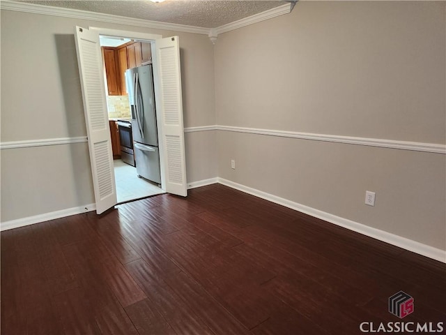 unfurnished room with dark wood-style floors, a textured ceiling, baseboards, and ornamental molding