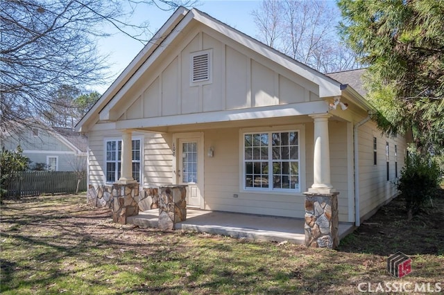 view of front facade featuring board and batten siding, fence, and a shingled roof