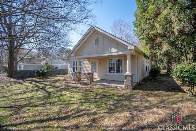 view of front of house with board and batten siding, a front yard, and fence