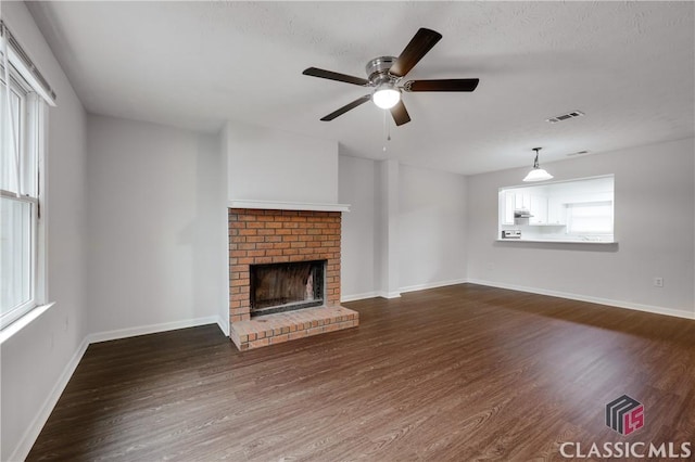 unfurnished living room with baseboards, a fireplace, visible vents, and dark wood finished floors