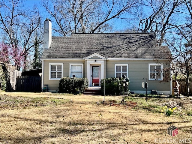 view of front of home featuring a chimney, a front lawn, and roof with shingles