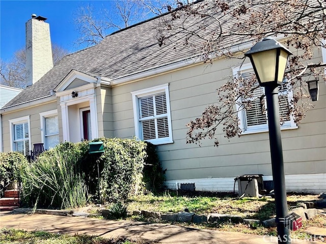 view of front of property featuring crawl space, a chimney, and roof with shingles