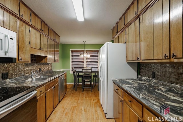 kitchen featuring dark countertops, light wood-style flooring, appliances with stainless steel finishes, and tasteful backsplash