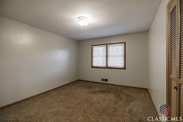 carpeted spare room featuring baseboards, visible vents, and a textured ceiling