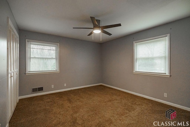 spare room featuring baseboards, carpet floors, visible vents, and a healthy amount of sunlight