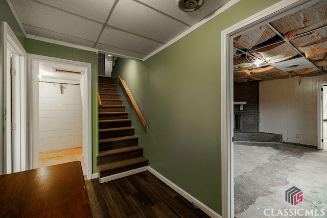 stairway featuring ornamental molding, a drop ceiling, baseboards, and wood finished floors