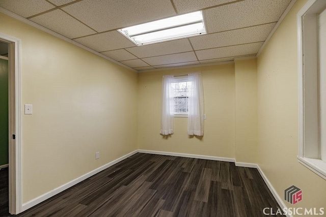 empty room featuring a paneled ceiling, baseboards, and dark wood-type flooring