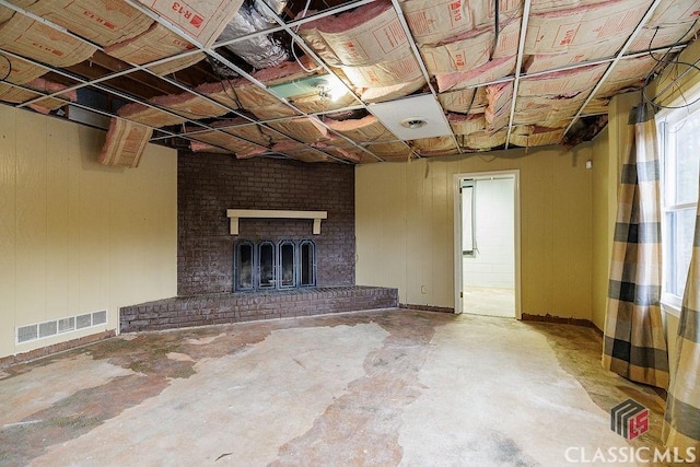 unfurnished living room featuring a brick fireplace, visible vents, and unfinished concrete flooring