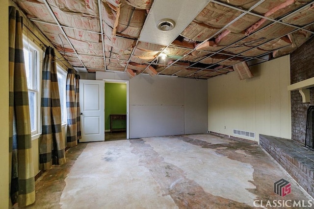 unfinished basement with a brick fireplace and visible vents