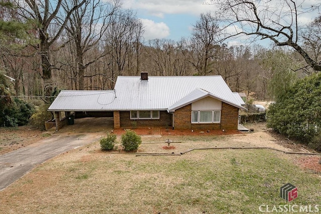 ranch-style house with metal roof, an attached carport, brick siding, driveway, and a front lawn