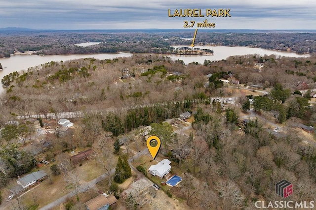 birds eye view of property with a water view and a wooded view