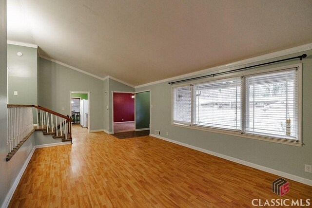 unfurnished living room featuring crown molding, stairway, vaulted ceiling, light wood-type flooring, and baseboards