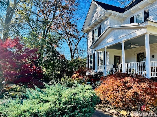 view of side of property featuring a porch and a ceiling fan