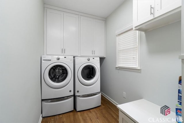 washroom with cabinet space, baseboards, separate washer and dryer, and wood finished floors