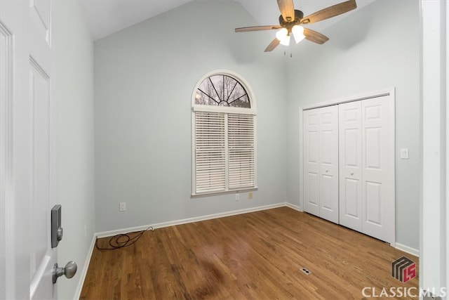 unfurnished bedroom featuring lofted ceiling, ceiling fan, wood finished floors, baseboards, and a closet