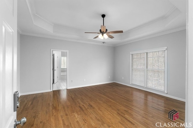 spare room featuring baseboards, a raised ceiling, ceiling fan, wood finished floors, and crown molding