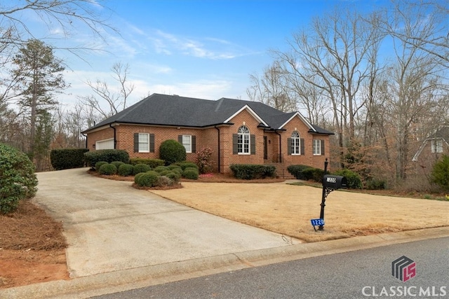 view of front of property with an attached garage, driveway, a front yard, and brick siding