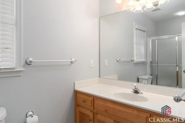 bathroom with vanity, a shower stall, and toilet