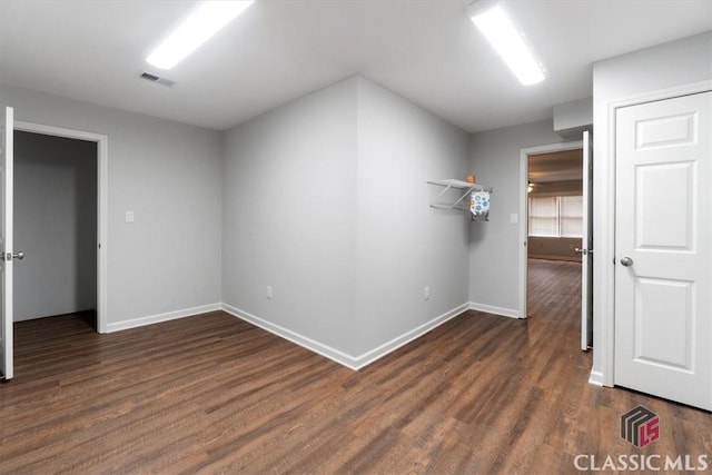 unfurnished room featuring wood finished floors, visible vents, and baseboards