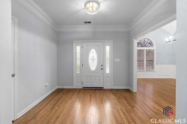 foyer featuring ornamental molding, visible vents, and light wood finished floors