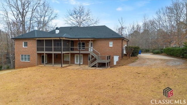 rear view of house featuring a sunroom, a patio area, brick siding, and stairway