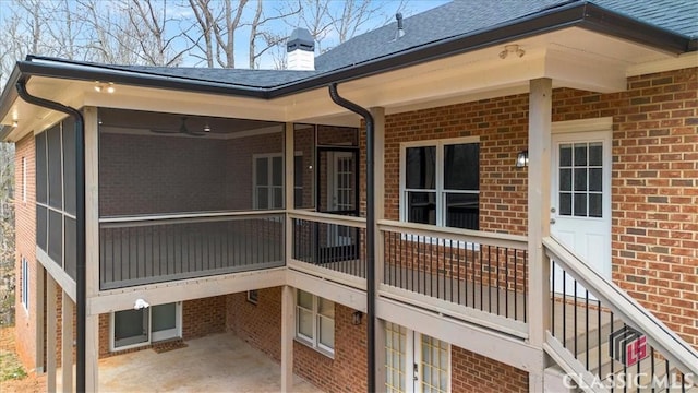 rear view of house featuring a sunroom, a chimney, and brick siding