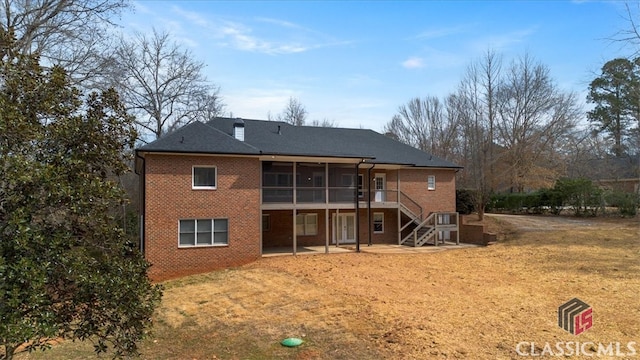 back of house with stairs, a patio, brick siding, and a sunroom