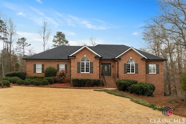 ranch-style house with a front lawn, a shingled roof, and brick siding