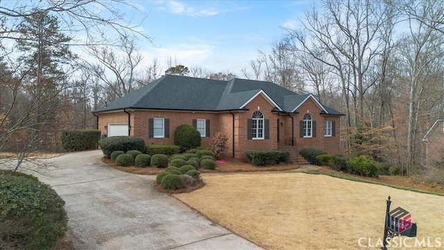 view of front of house with a garage, a front yard, concrete driveway, and brick siding