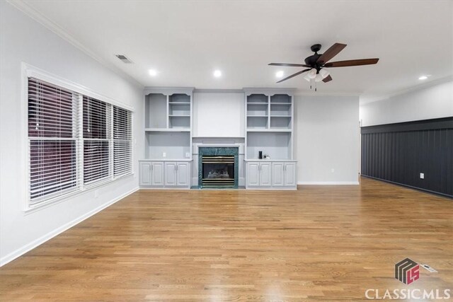 unfurnished living room featuring light wood-type flooring, a fireplace, visible vents, and crown molding