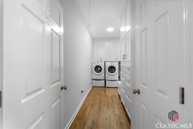 laundry area featuring separate washer and dryer, wood finished floors, cabinet space, and baseboards