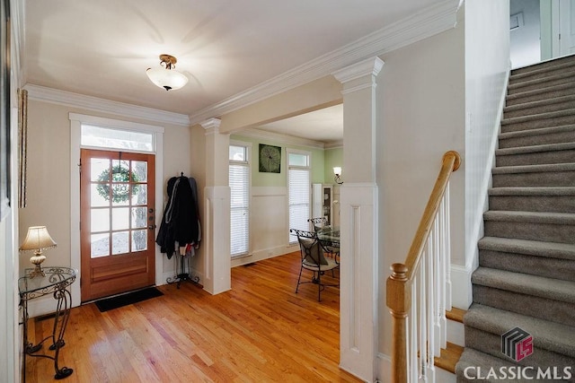 entrance foyer featuring ornamental molding, light wood finished floors, ornate columns, and stairs