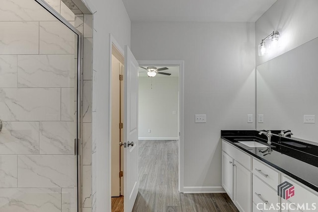 full bath featuring baseboards, ceiling fan, wood finished floors, vanity, and a shower stall