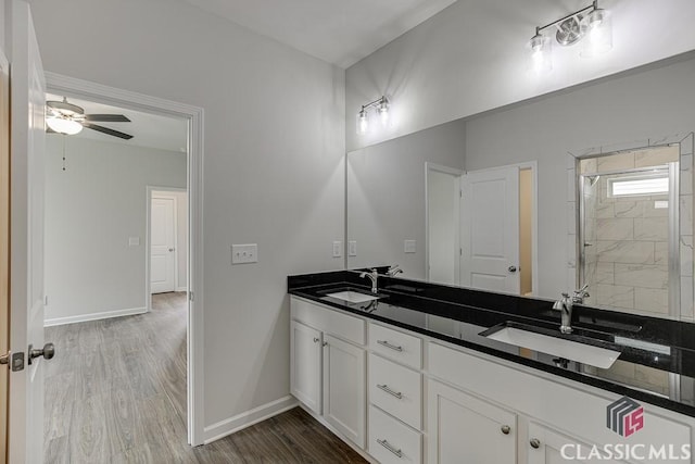 bathroom featuring double vanity, a sink, baseboards, and wood finished floors