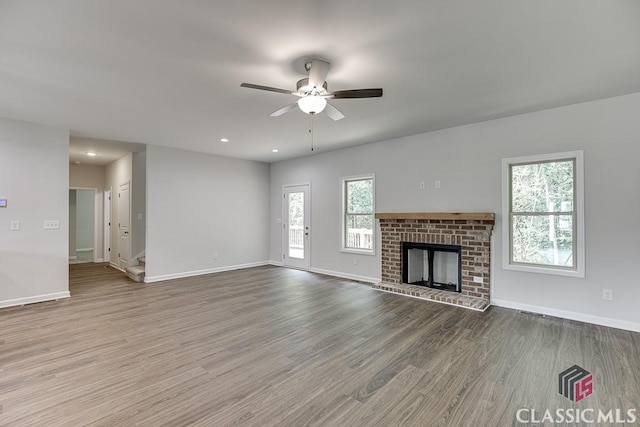 unfurnished living room featuring recessed lighting, a fireplace, wood finished floors, a ceiling fan, and baseboards