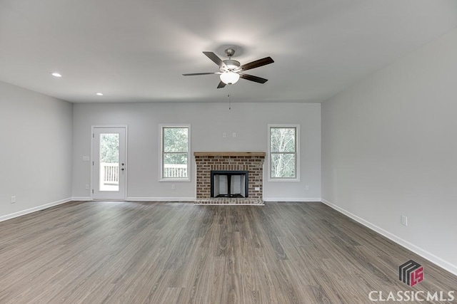 unfurnished living room featuring recessed lighting, a ceiling fan, a brick fireplace, wood finished floors, and baseboards