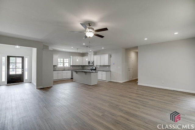 kitchen featuring open floor plan, stainless steel microwave, dark countertops, and backsplash