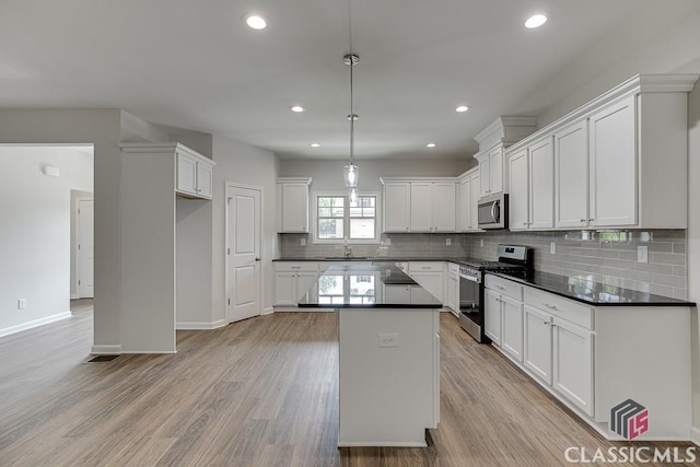 kitchen featuring dark countertops, light wood-type flooring, appliances with stainless steel finishes, and a sink