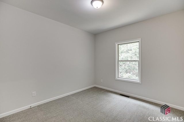 unfurnished room with carpet, visible vents, and baseboards