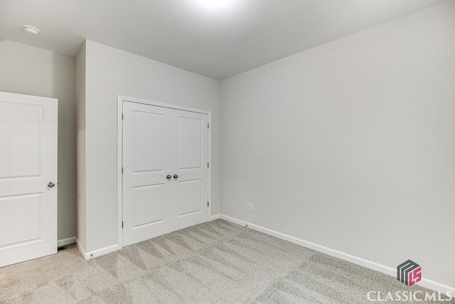 unfurnished bedroom featuring carpet floors, baseboards, and a closet