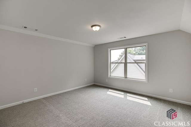 carpeted spare room featuring lofted ceiling, visible vents, crown molding, and baseboards