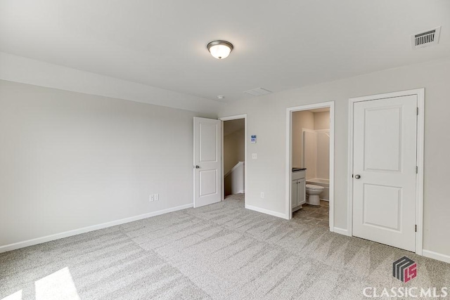 unfurnished bedroom with light colored carpet, visible vents, ensuite bath, and baseboards