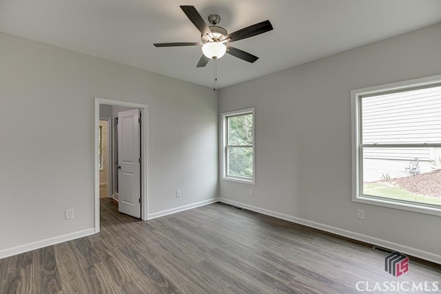 empty room with ceiling fan, visible vents, baseboards, and wood finished floors