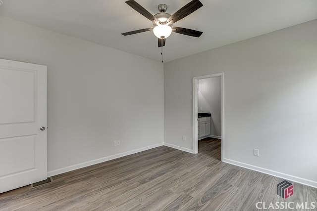 unfurnished bedroom featuring visible vents, baseboards, a ceiling fan, connected bathroom, and wood finished floors